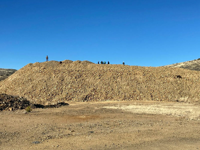 Mine waste on the landscape in Copper Flat, N.M., with USGS staff just visible on top.